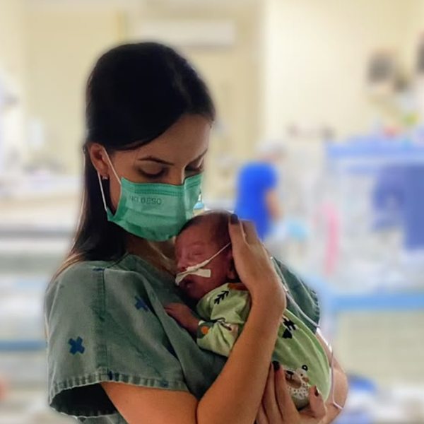 Dra. Amanda Rocha acolhendo no colo um bebê prematuro na UTI neonatal